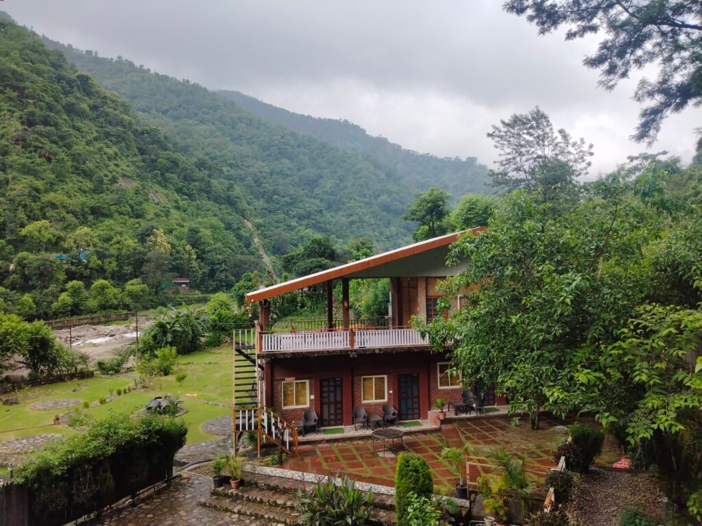 Scenic wooden cottage surrounded by lush green hills at King's Retreat in Dehradun