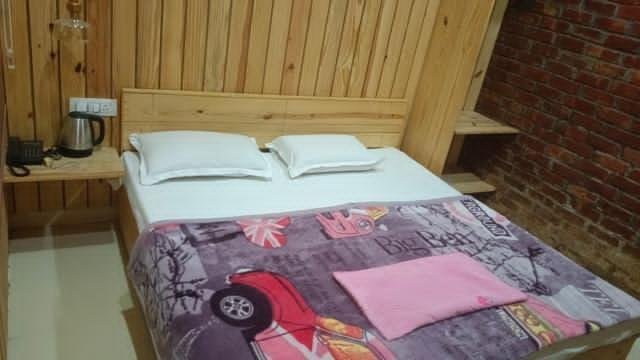 Cozy double bed with soft pillows and pink blanket in a wooden cottage.